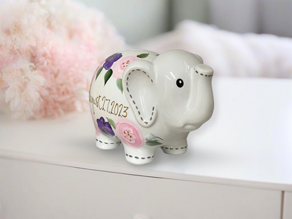 Hand-painted piggy bank adorned with delicate purple and pink flowers, offering a charming and personalized touch.